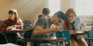 Studenci siedzą w szkolnych ławkach, uczą się i rozmawiają razem.