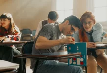 Jak zadbać o równowagę między nauką a życiem prywatnym Studenci siedzą w szkolnych ławkach, uczą się i rozmawiają razem.