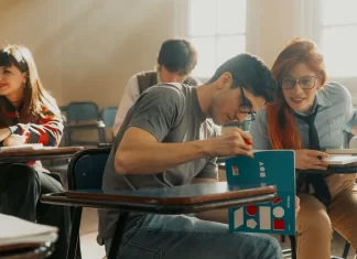 Jak zadbać o równowagę między nauką a życiem prywatnym Studenci siedzą w szkolnych ławkach, uczą się i rozmawiają razem.